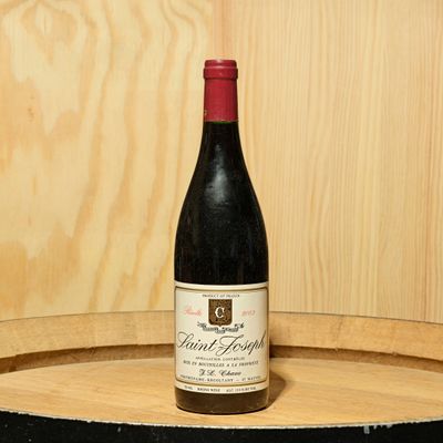 a bottle of wine sitting on top of a barrel