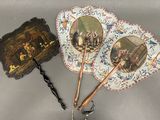 trois éventails anciens ornés de portraits, posés sur une table