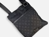 Le petit sac à bandoulière est noir et possède une bandoulière noire.