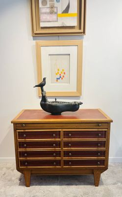 une commode en bois surmontée d'une sculpture d'oiseau