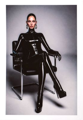 lady in black latex sitting in a chair with her legs crossed