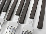 several forks and knives are lined up on a white surface