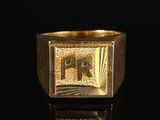 a close up of a gold ring with the letter f on it
