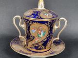 une tasse et une soucoupe bleues et dorées ornées d'un oiseau