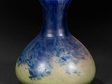 a blue and yellow vase sitting on a black surface