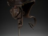 an old helmet on a metal stand with a black background