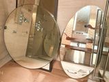 a bathroom with a large round mirror and a walk in shower