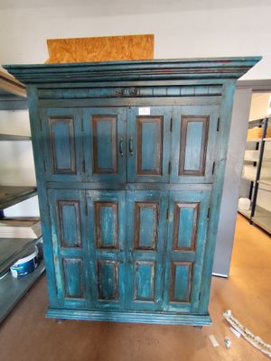 une armoire bleue au milieu d'une pièce, à côté d'un lit