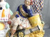 two figurines of a man and a woman sitting on a bench