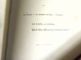 un livre ouvert posé sur une table, à côté d'un livre rouge