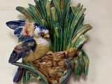 deux oiseaux posés dans un panier accroché au mur