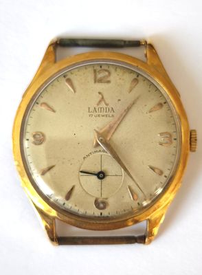 une montre-bracelet en or posée sur une surface blanche
