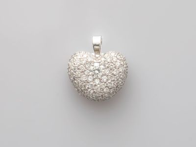 un pendentif en forme de cœur en or blanc et diamants sur fond blanc