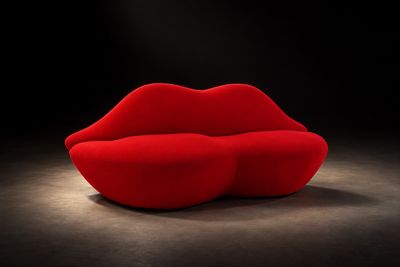 un canapé rouge sur lequel est dessinée une lèvre rouge, dans une pièce sombre