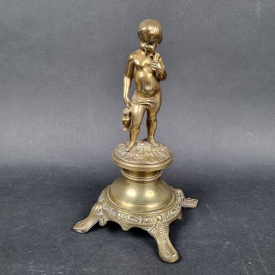 brass figurine of a boy holding a bird on a pedestal
