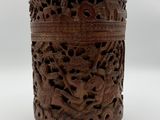 une vieille boîte en bois sculptée posée sur une surface blanche