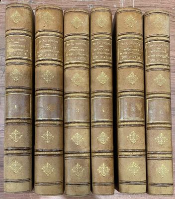 six vieux livres sont alignés sur une table en bois