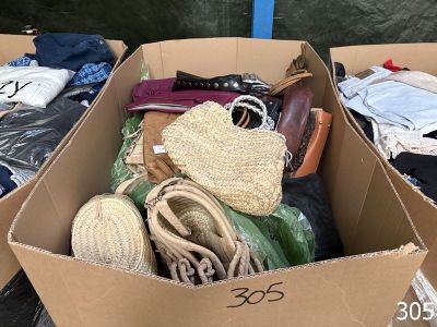 a cardboard box full of clothes and bags on the ground