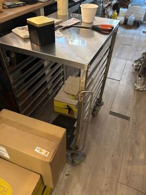 a kitchen with a stainless steel table and boxes on the floor