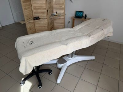 une table de massage recouverte d'un drap, dans une pièce