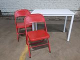 deux chaises rouges et une table blanche dans un parking