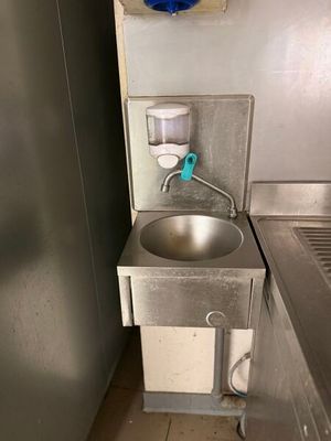 un évier dans un coin de la cuisine, avec une poubelle bleue
