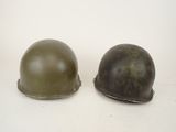 pair of army helmets on a white surface with a white background