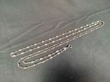 two silver chains are laying on top of a black cloth