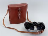 an old pair of binoculars sitting next to a leather case