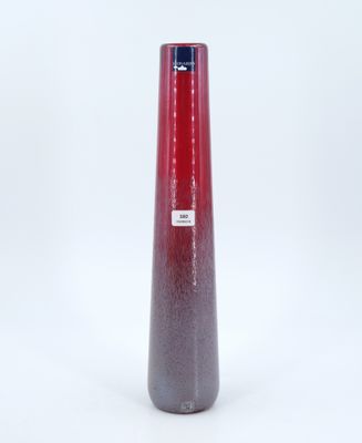 un vase rouge posé sur une surface blanche