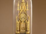 a gold clock under a glass dome on a table
