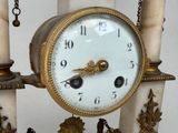 a clock that is hanging on a pillar with chains