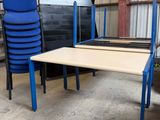 plusieurs chaises et une table dans un entrepôt où se trouve une pile de chaises