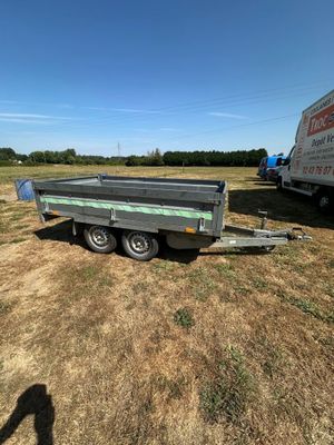une remorque vide garée dans un champ, avec un camion derrière