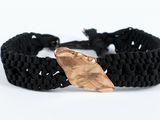 un gros plan d'un bracelet noir orné d'une feuille en cuivre