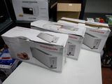 Quatre boîtes de micro-ondes sont empilées sur une table dans une pièce.