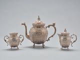 three pieces of silver tea and coffee set on a table