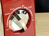 a close up of a red toaster on a wooden table