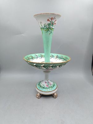 une photo d'un vase vert et blanc posé sur un socle