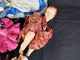 a doll that is laying on a bed with other dolls