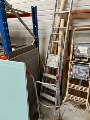 a ladder leaning against a wall next to a pile of assorted items