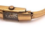 a gold bracelet with a watch on it on a white surface