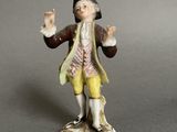 figurine of a man with a hat and yellow pants holding his hands up