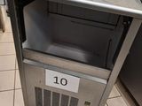 une petite machine à glaçons posée par terre dans la cuisine