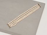 un gros plan d'un bracelet de perles blanches posé sur une surface grise