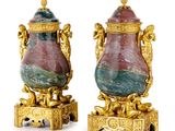 une paire de vases en or et en marbre sur socles, sur fond blanc