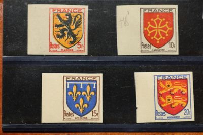 quatre timbres représentant différents blasons, posés sur une table