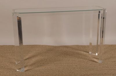 une photo d'une console en verre transparent posée sur un sol recouvert de moquette