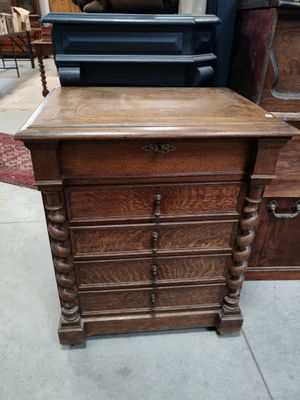 une commode ancienne en bois avec des tiroirs et une chaise à l'arrière-plan