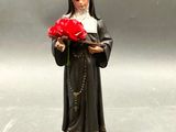 figurine représentant une religieuse tenant une rose rouge dans ses mains